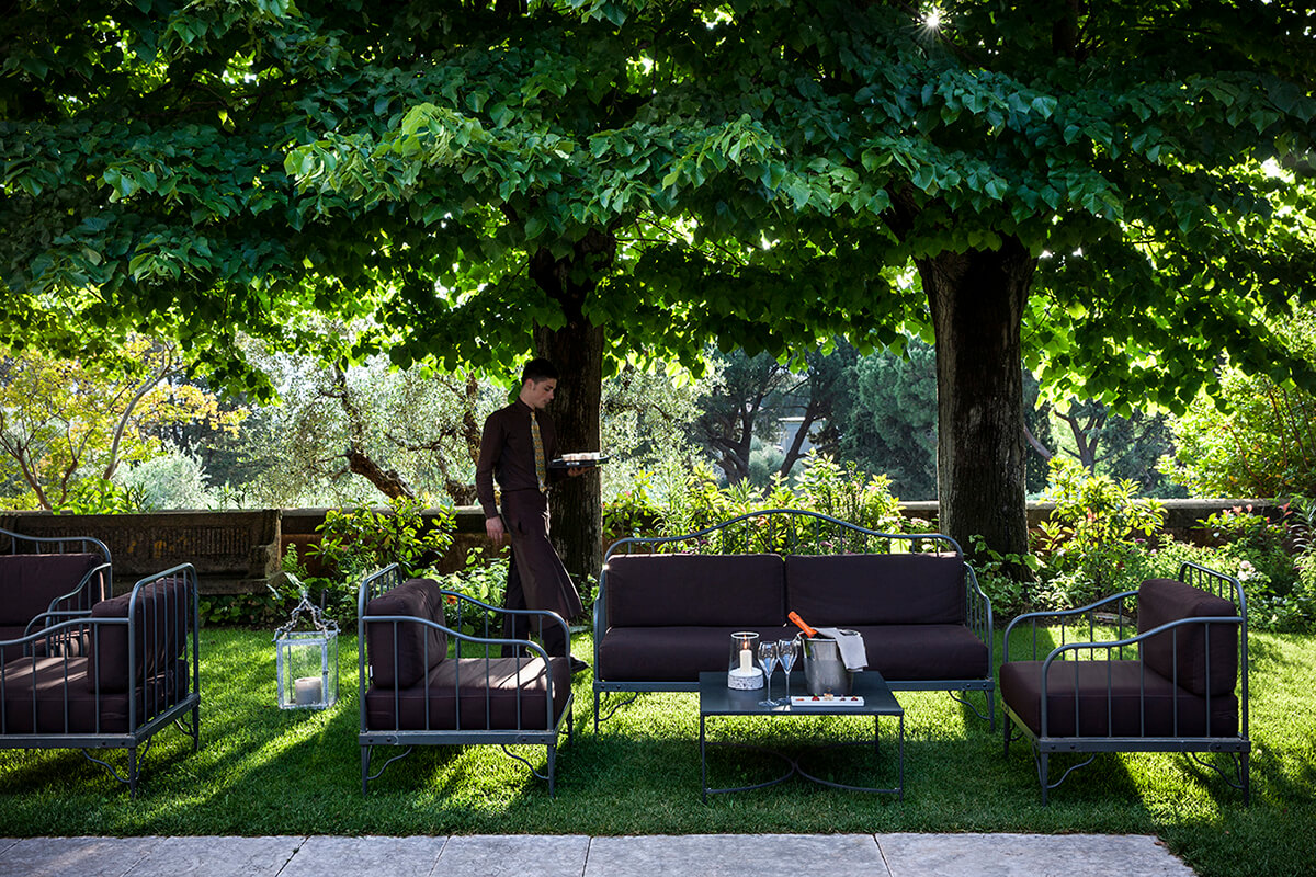 Outdoor sofas and table with waiter serving champagne on the lawn