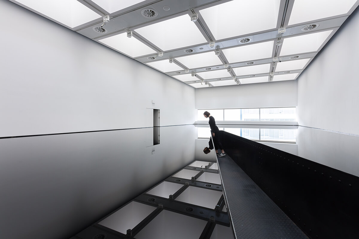 Richard Wilson's room full of oil with a person leaning over and reflection of the ceiling