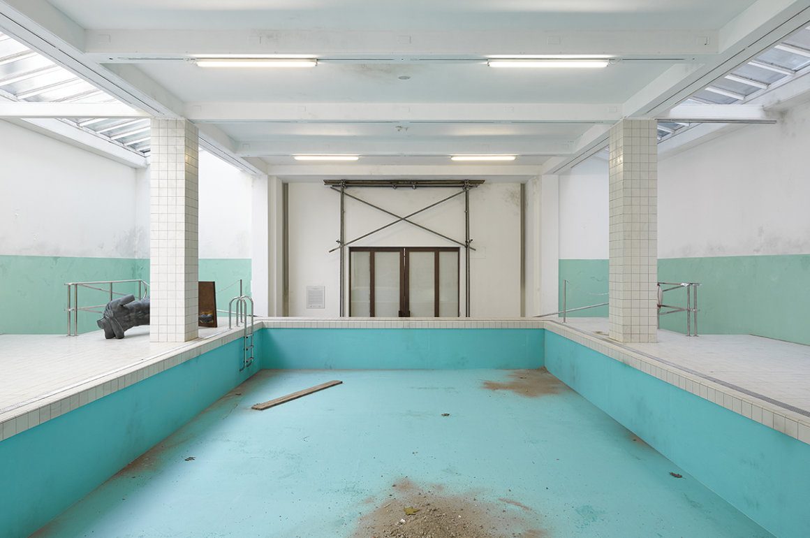 Image of an old empty swimming pool with a turquoise surface