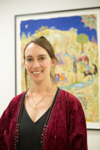 Portrait of artist Hana Louise Shahnavaz standing in front of one of her works