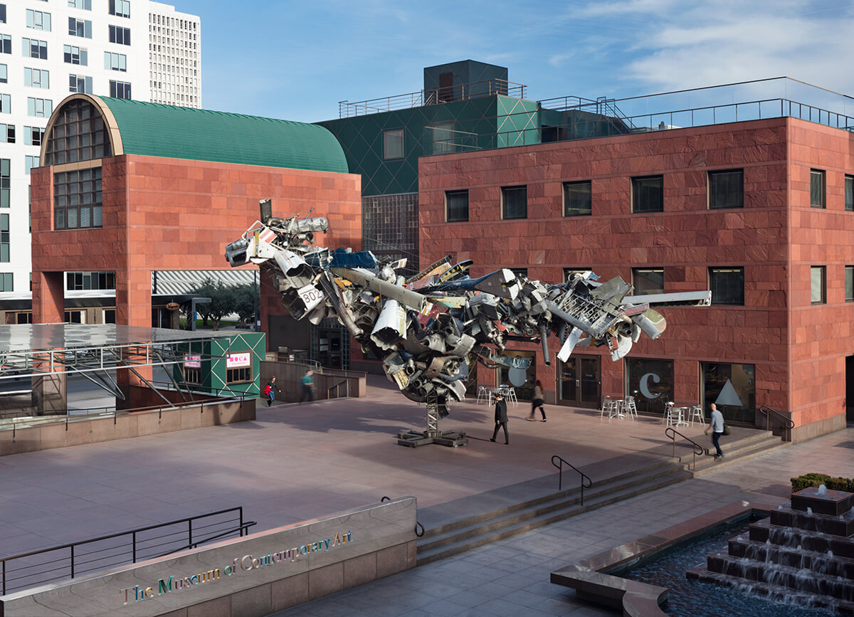 Facade of a red building with a public installation in a courtyard