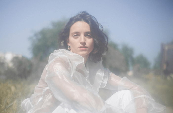 Washed out image of Girl sitting in a field in a white dress