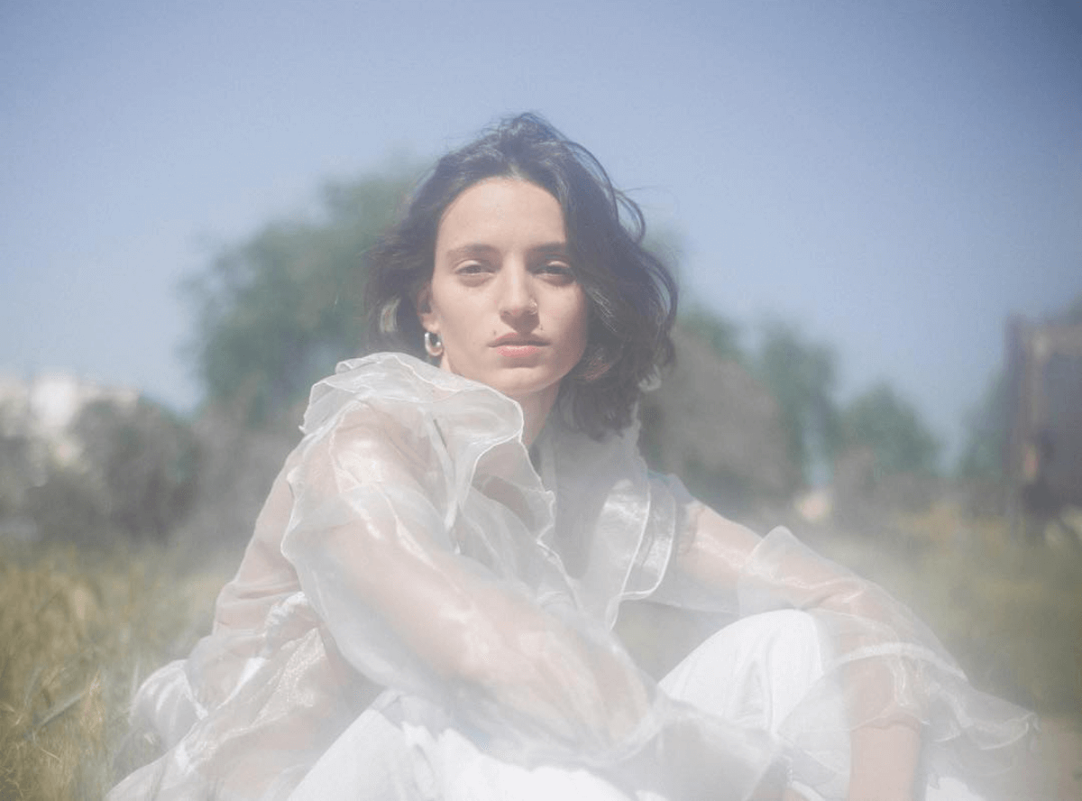 Washed out image of Girl sitting in a field in a white dress