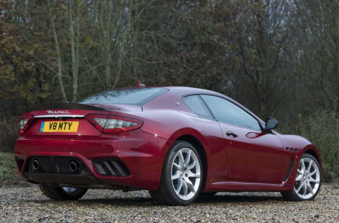 Maroon Maserati GranTurismo sportscar pictured on a drive in the woods