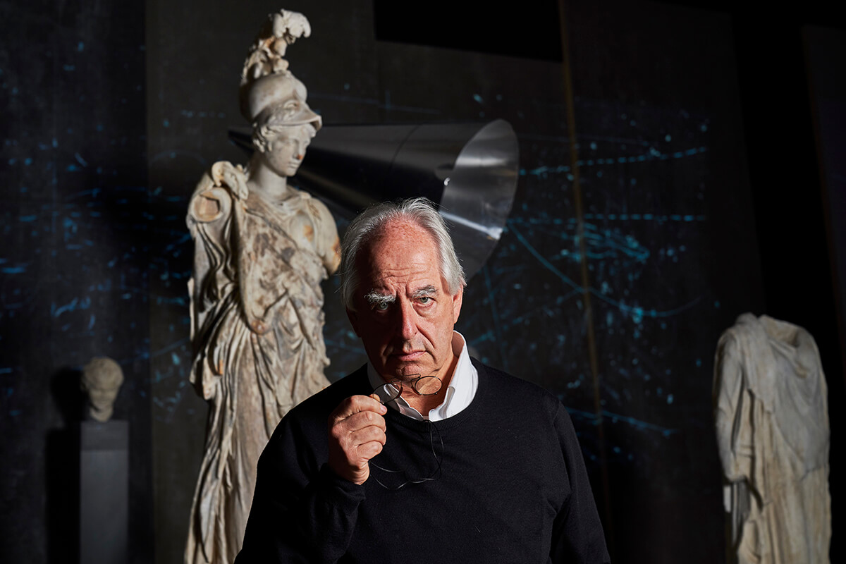 Portrait of south african artist willima kentridge standing in front of a stone sculpture
