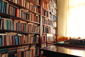 Vintage library scene with wooden bookshelves and a table and chair at the window