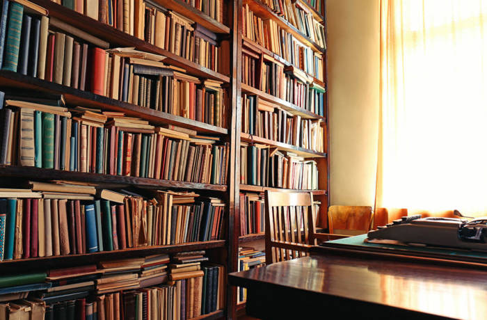 Vintage library scene with wooden bookshelves and a table and chair at the window