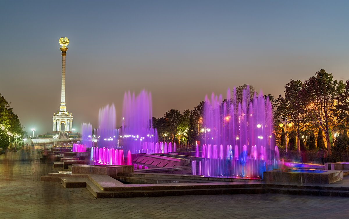 independence monument in Dushanbe with water fountains lit with purple lights