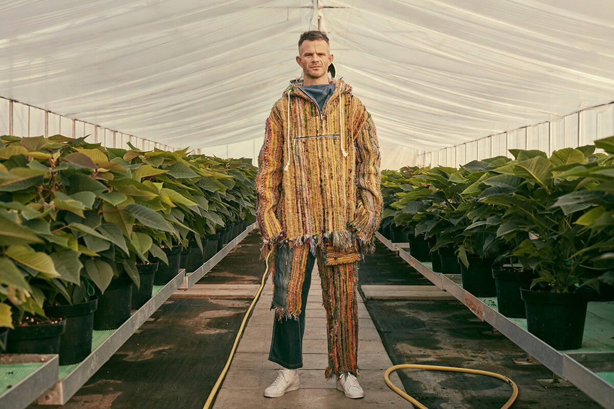 Man standing in greenhouse wearing high fashion apparel 