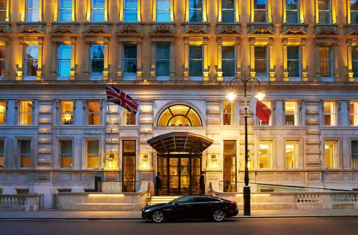 Grand hotel entrance with british flag flying at the doorway, a car parked outside and lights glowing from the windows