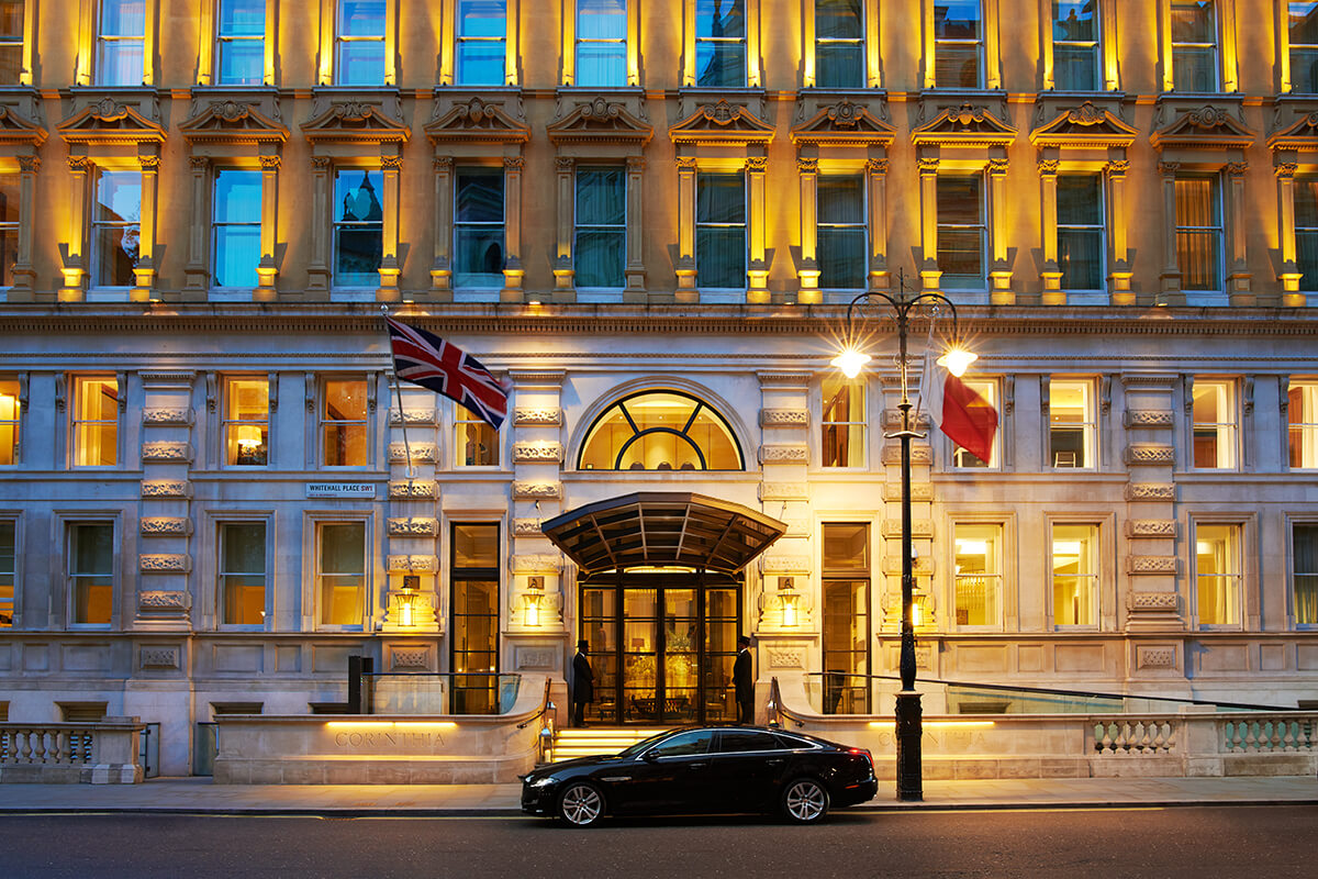 Grand hotel entrance with british flag flying at the doorway, a car parked outside and lights glowing from the windows