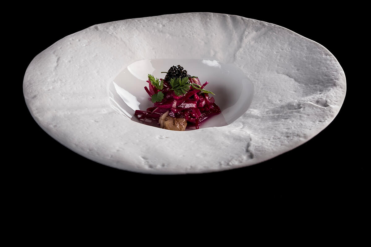 Detail image of a white bowl with vibrant purple vegetarian dish at the centre