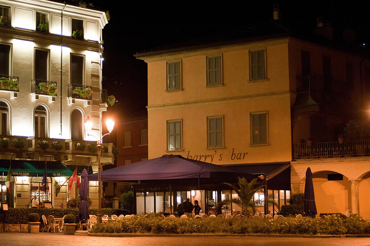 Image of traditional Italian restaurant at night with tables underneath a mauve awning