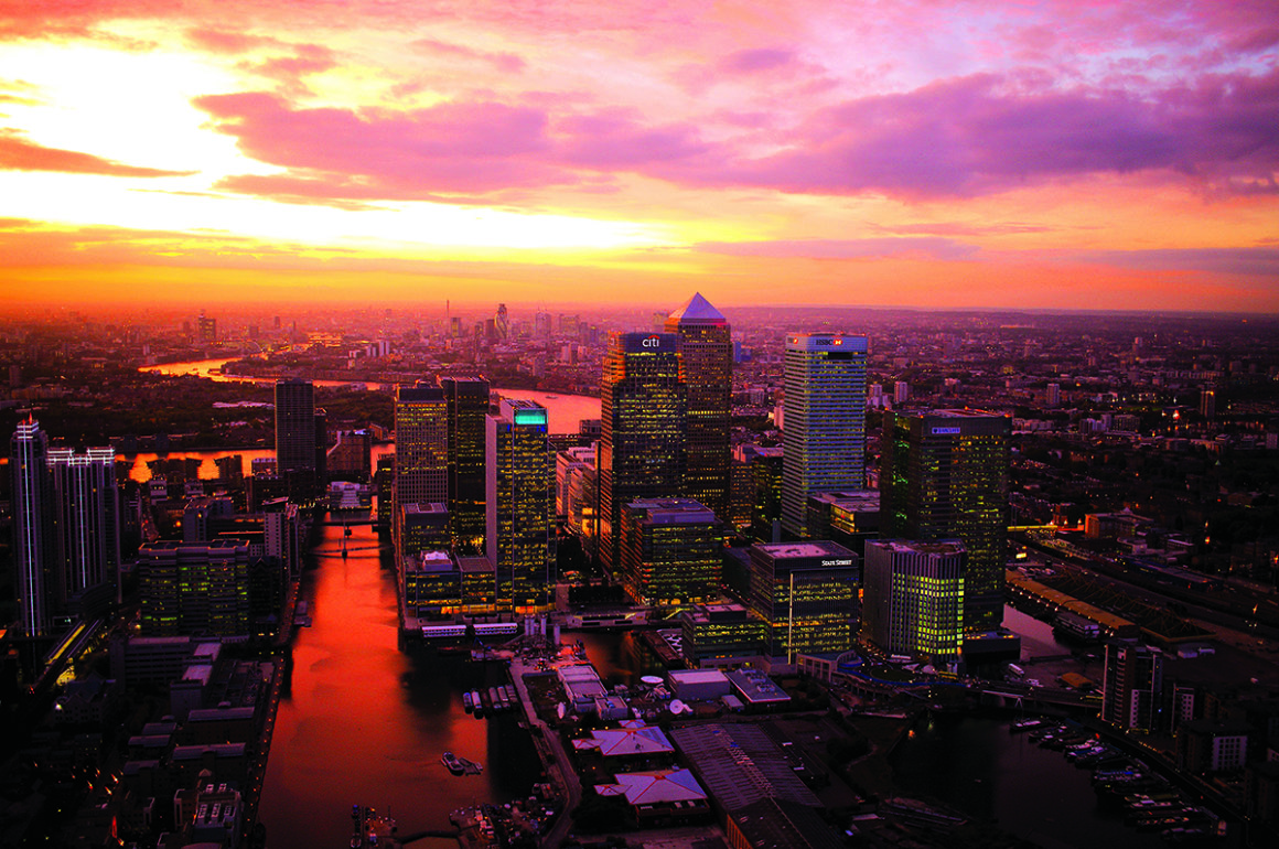 Bird's eye shot of Canary Wharf, London at night with a sunset sky