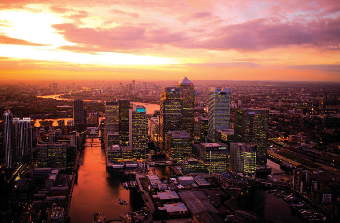 Bird's eye shot of Canary Wharf, London at night with a sunset sky