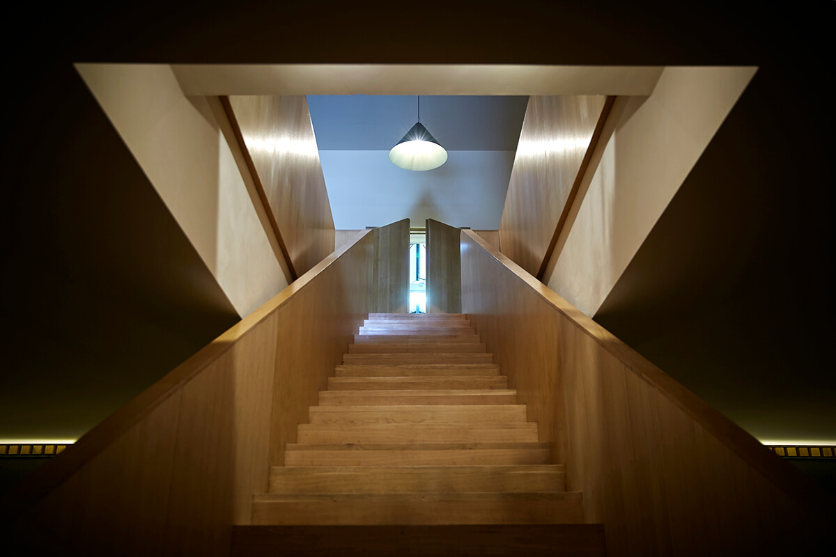 Architectural photograph of stairway leading up to a landing with a hanging light