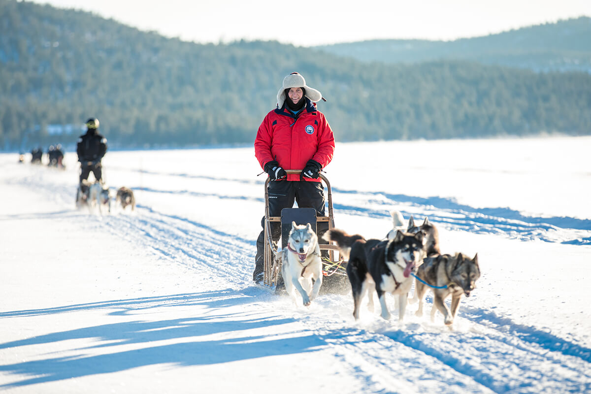 Geoffrey Kent riding a dog sled through the snow