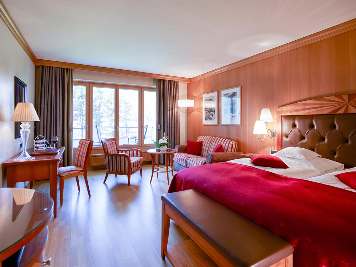 A traditional style luxury hotel bedroom with wood panelled walls and red furnishings