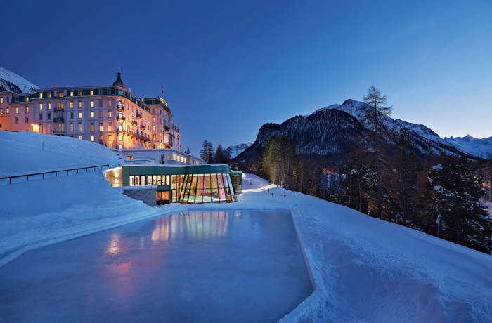 Ski resort hotel pictured at night with an indoor swimming pool and ice rink