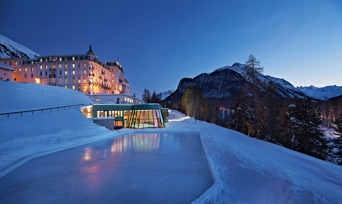 Ski resort hotel pictured at night with an indoor swimming pool and ice rink