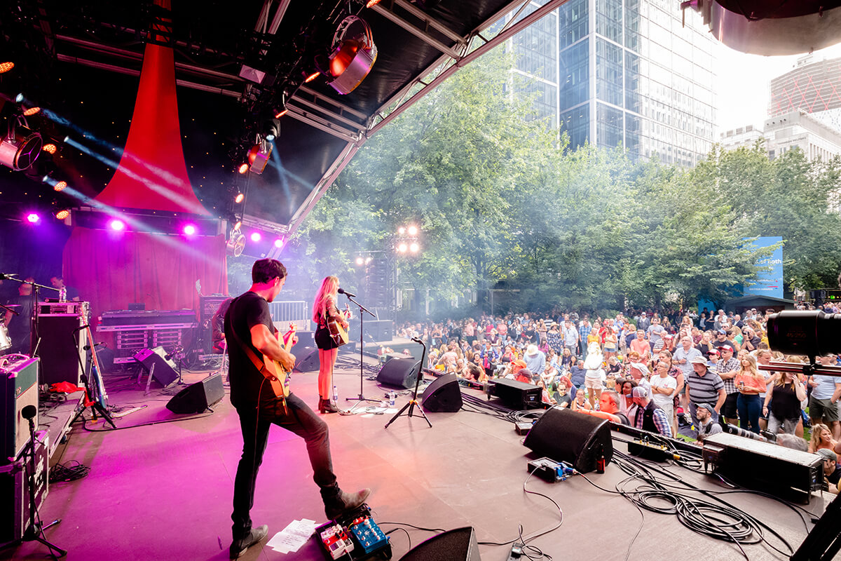 Shot from behind the stage at a music festival looking out at the crowds enjoying the music