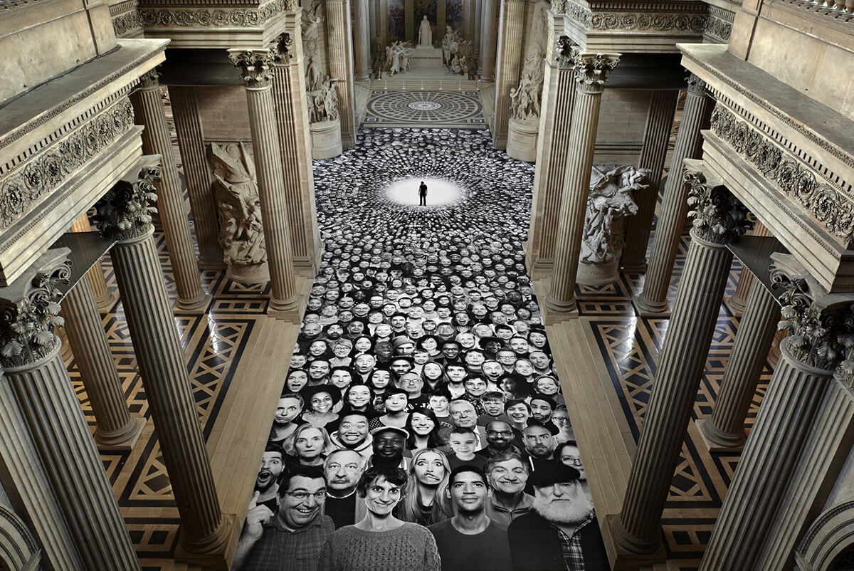 Large scale installation of black and white faces pasted onto the floor of a Paris museum by artist JR