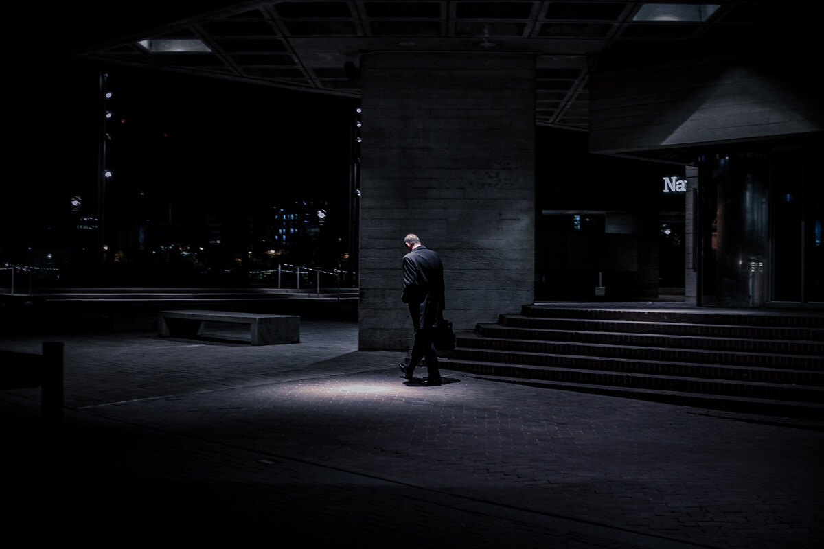 artistic photograph of a man walking at night through a concrete landscape