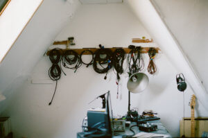 Image of a home recording studio with wires hanging on hooks on the wall and a desk