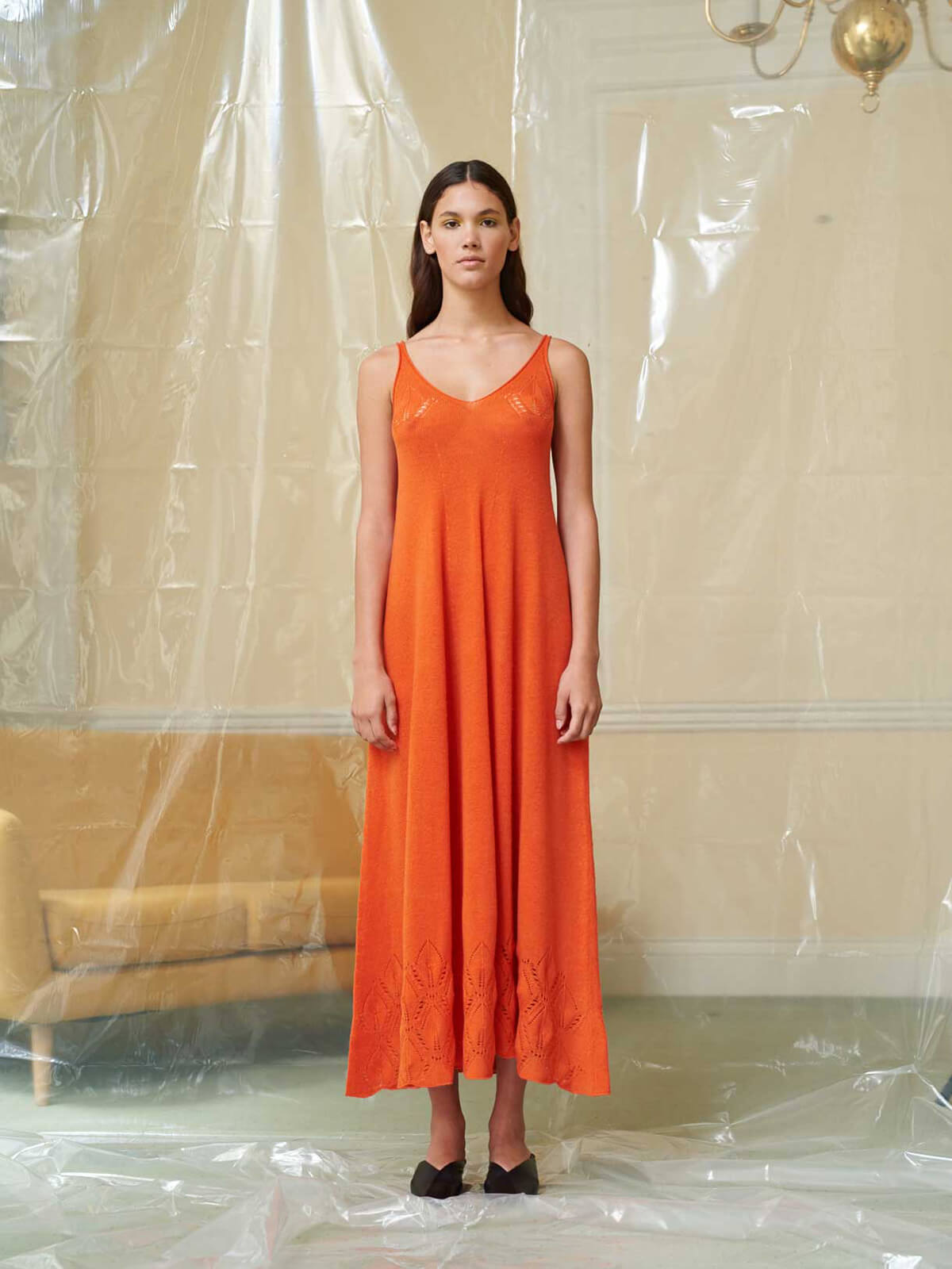 Model poses wearing an orange slip dress
