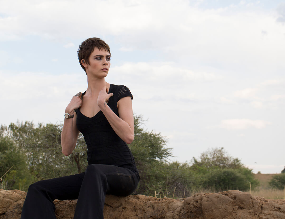 British model Cara Delevingne sits on mound of earth in the African bush wearing all black for TAG Heuer campaign