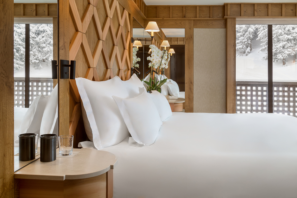 Luxury ski hotel bedroom with a double bed and windows looking onto snowy landscape