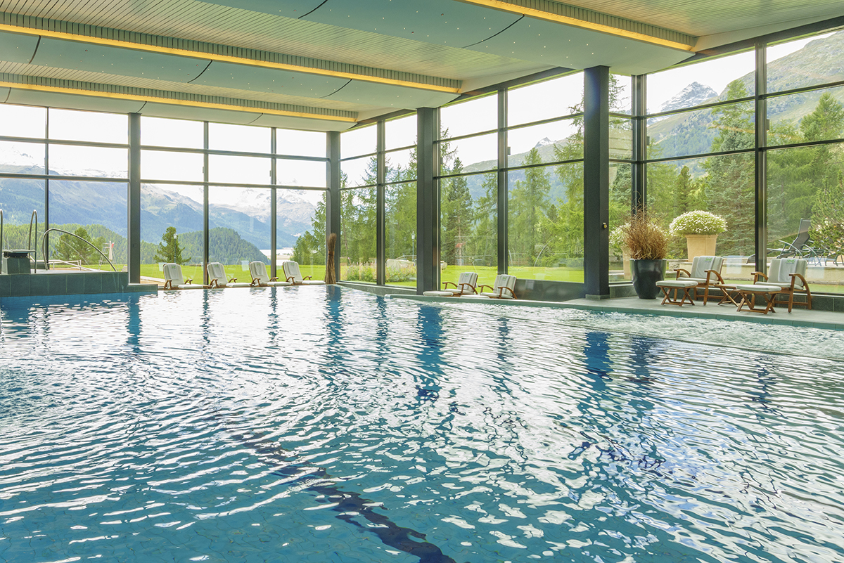 Luxury indoor swimming pool surrounded by glass windows