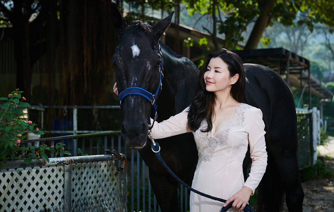 Business woman Vicky Xu poses with a black horse