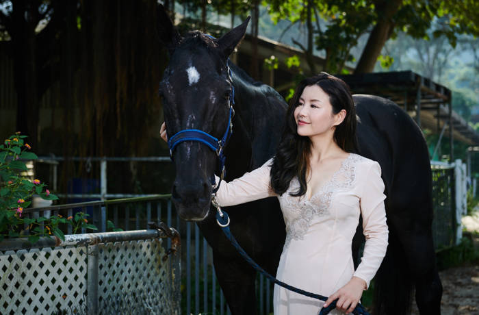 Business woman Vicky Xu poses with a black horse