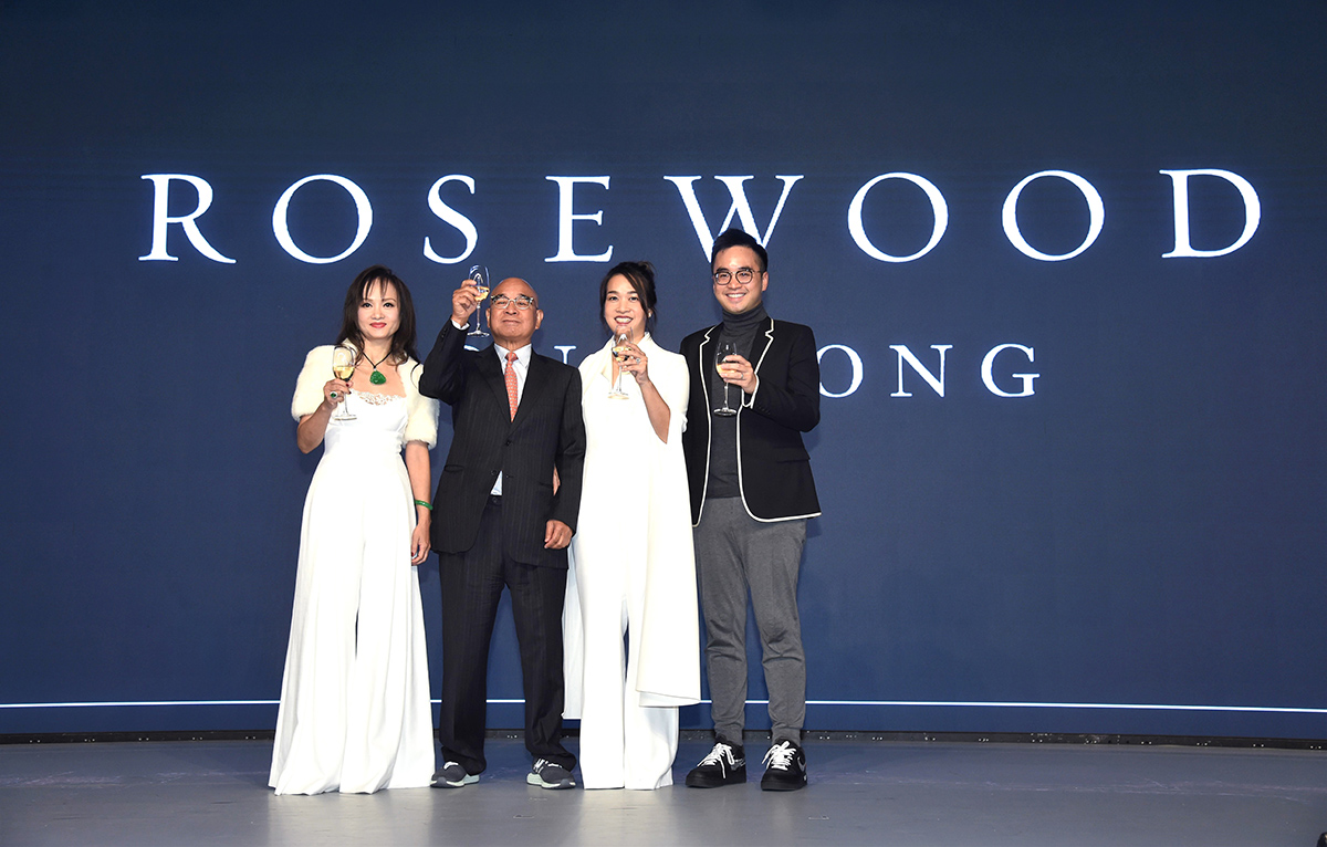 Four people standing on a stage in front of Rosewood Hong Kong sign