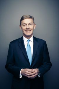 Portrait of a middle aged business man wearing a blue suit jacket and bright blue tie