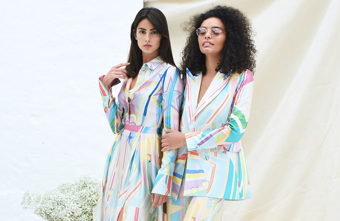 Two female models pose in candy coloured suit and dress