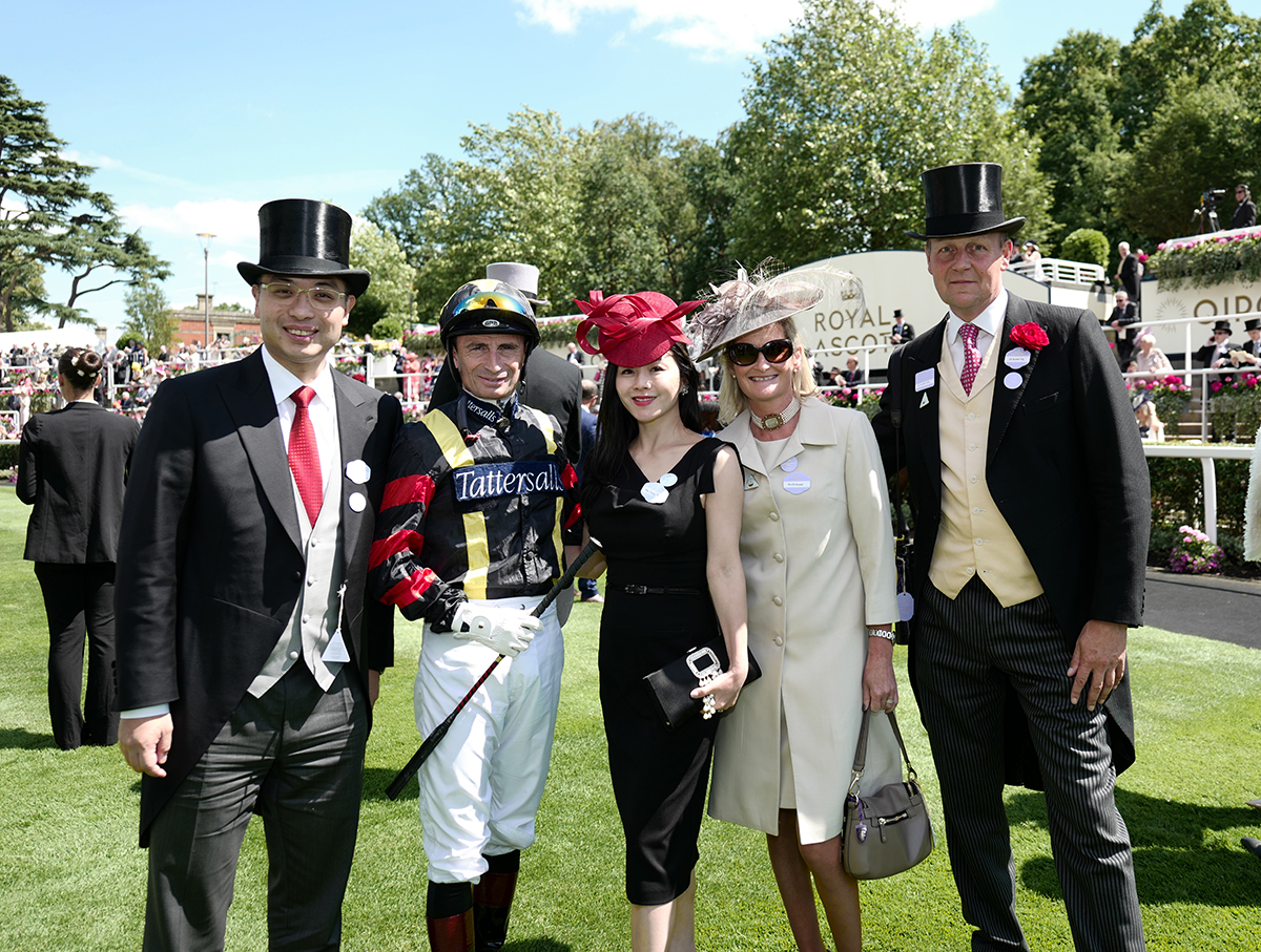 Guests at royal ascot pose with jockey on the track