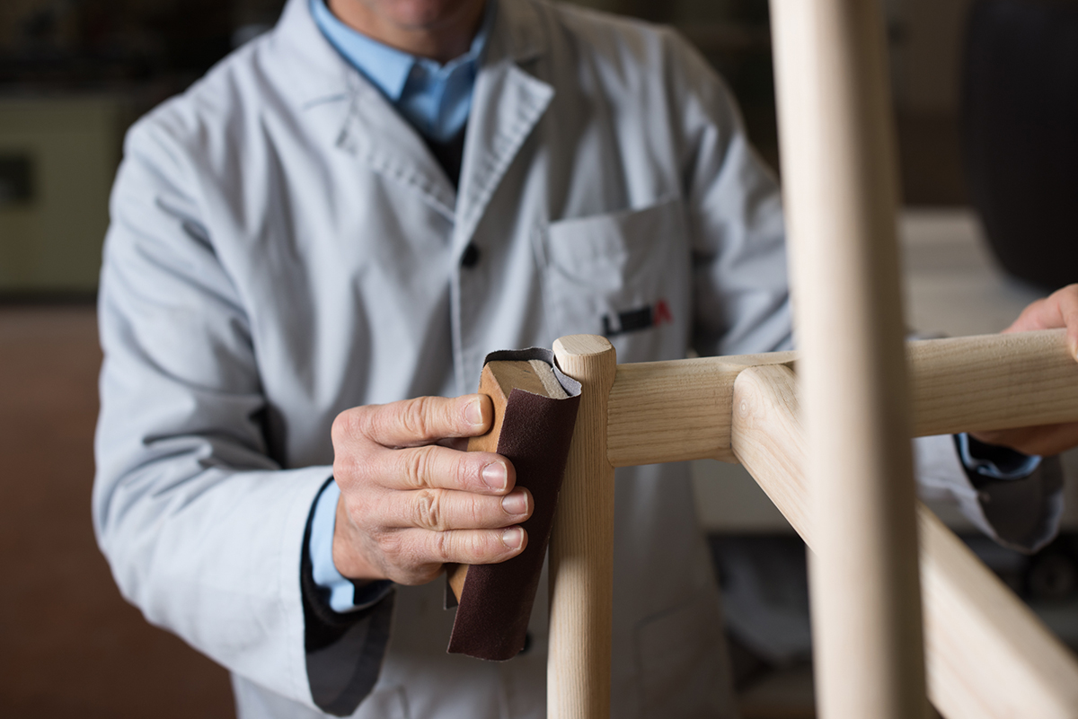 Craftsman sanding the edge of a piece of furniture