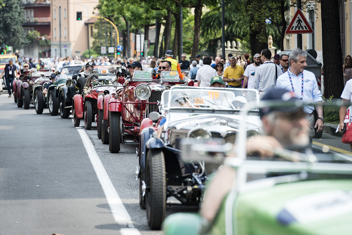 A line of classic cars passing along a road