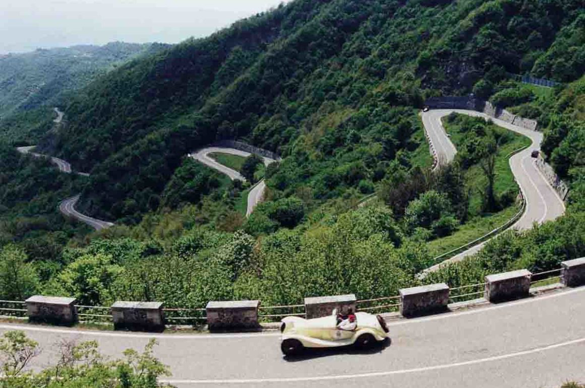 A classic car driving along a mountainous road