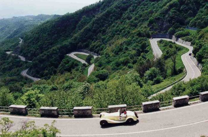 A classic car driving along a mountainous road