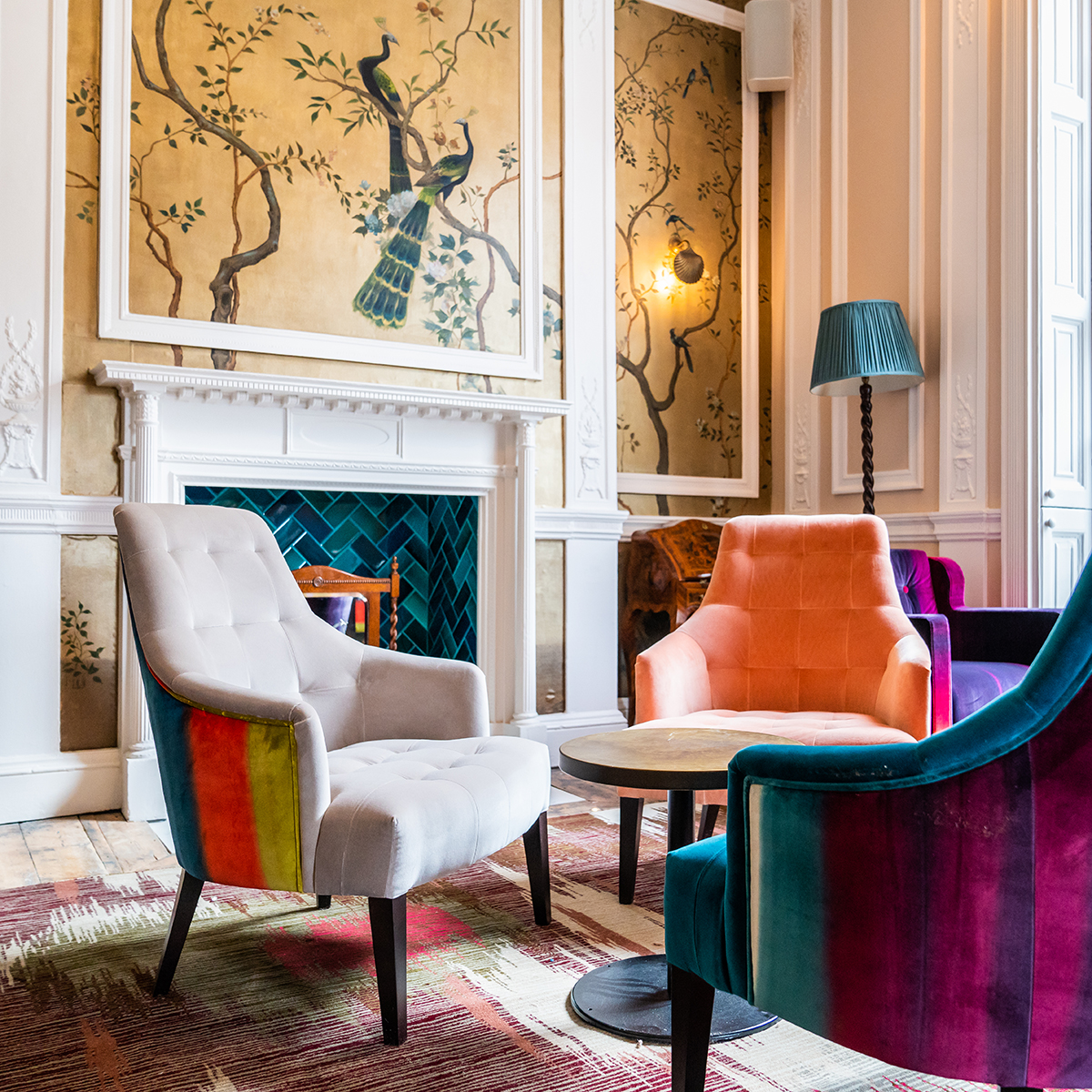 Colourful interiors of a living room with velvet arm chairs and illustrated walls