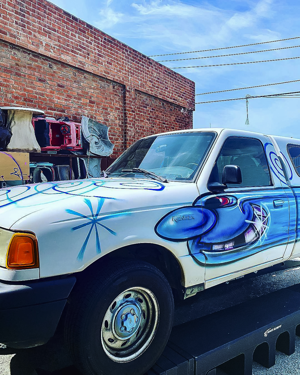 Kenny Scharf painting on the side of a truck parked by a brick wall