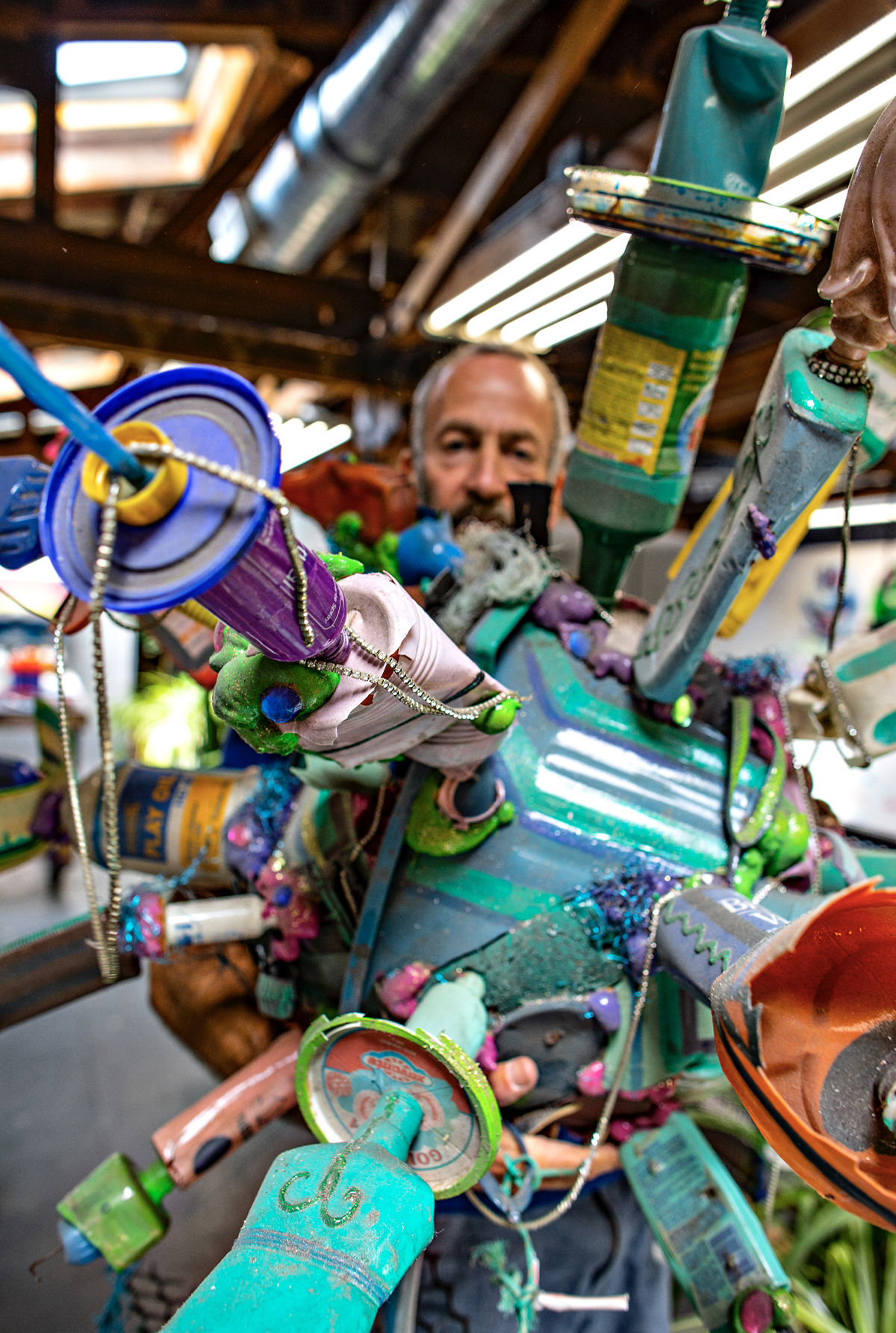 artist Kenny scharf poses in his studio with a sculpture