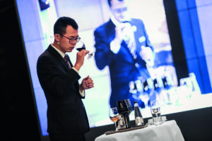 A sommelier smells a glass of red wine