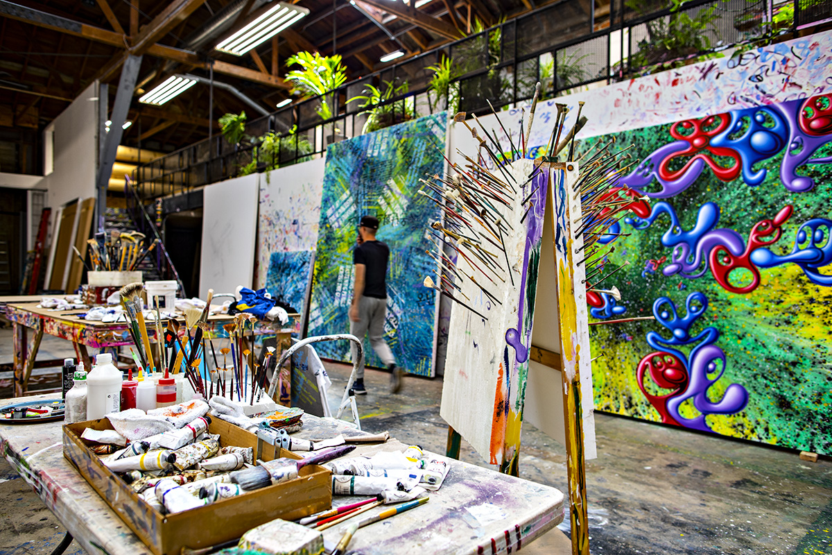 Artist studio with huge painted canvases and paint brushes