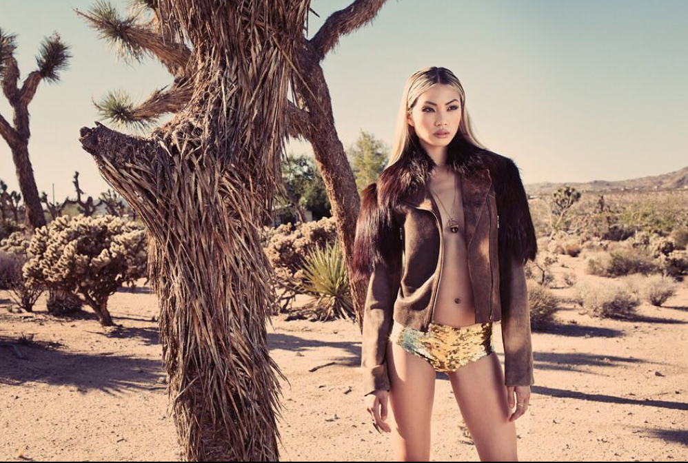 Asian model stands in desert setting wearing a bikini and jacket