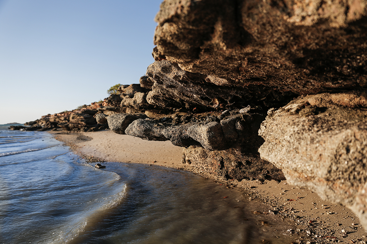 A rocky beach cove with low overhanging cliffs