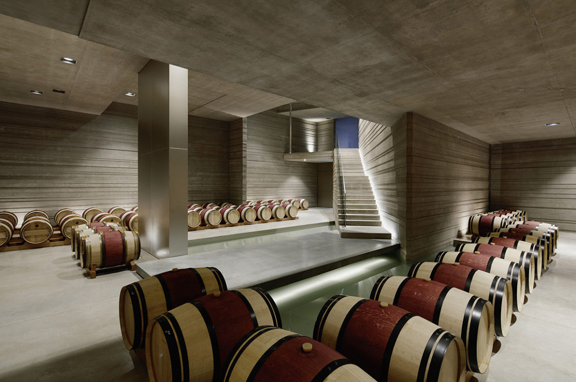 Underground wine cellar with wooden barrels and concrete walls and ceilings
